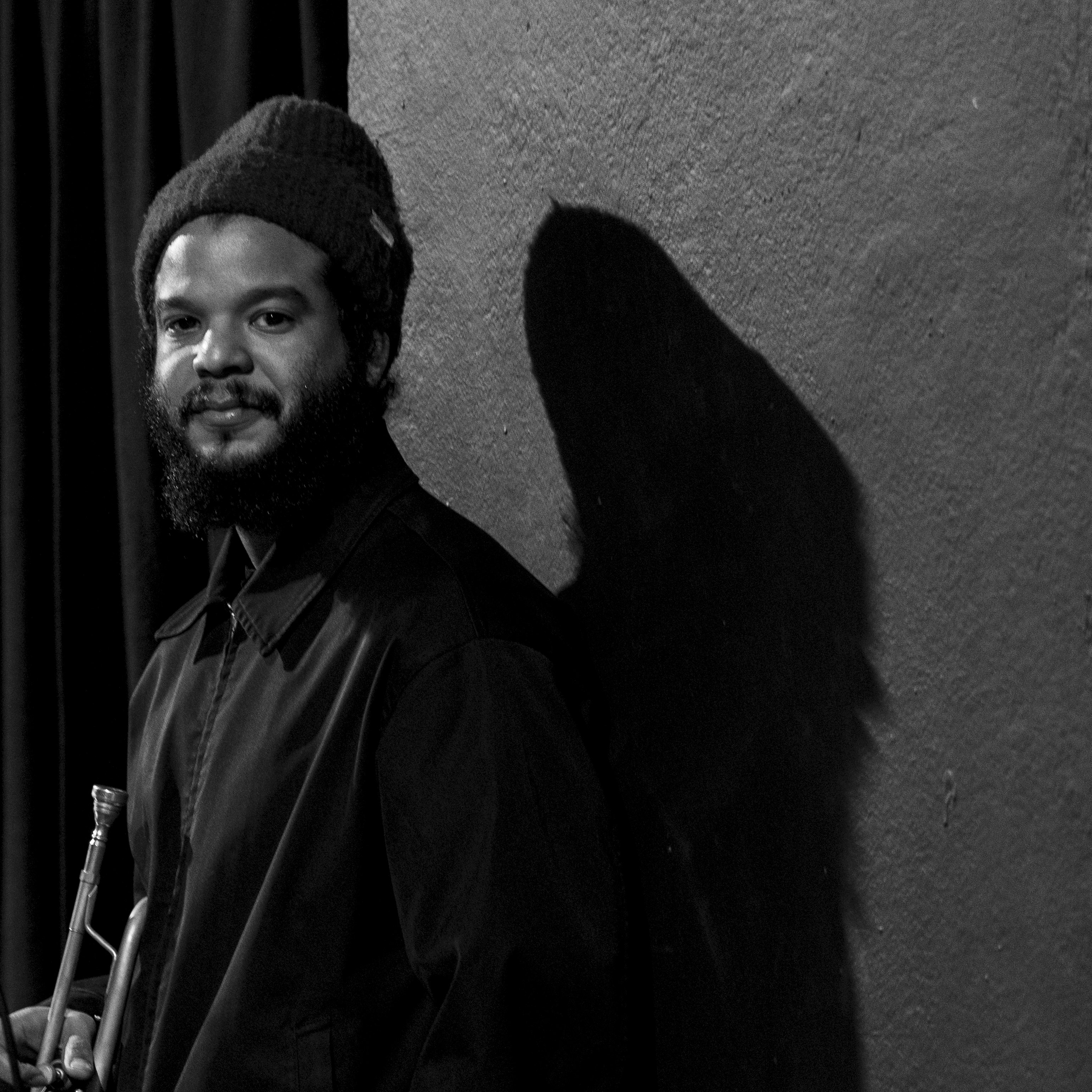 A black and white portrait of Aquiles Navarro, leaning against a wall. Credit: Roberto Garofalo